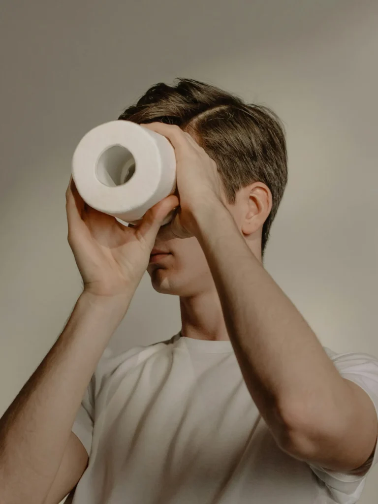 Teenage boy looking through a toilet roll