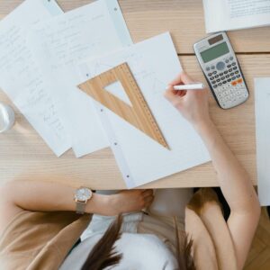 An overhead view of a student studying geometry using a calculator and notes at home. Perfect for education visuals.