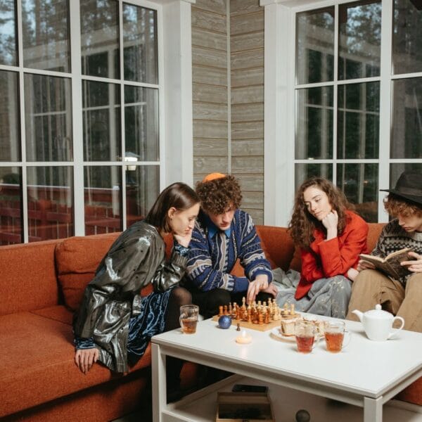 Friends playing chess and reading indoors, creating a cozy and focused atmosphere.