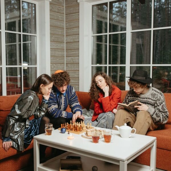 Friends playing chess and reading indoors, creating a cozy and focused atmosphere.
